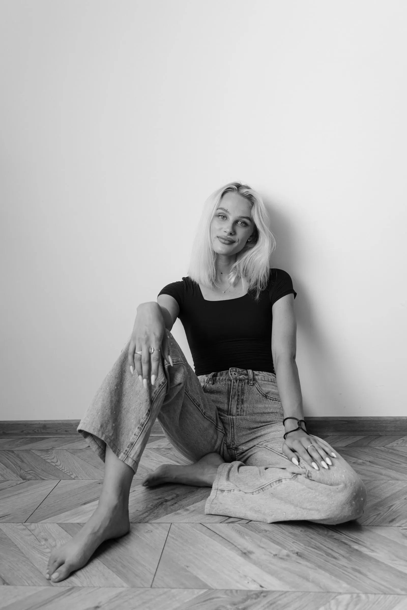 Žena sedí na parketách pri stene