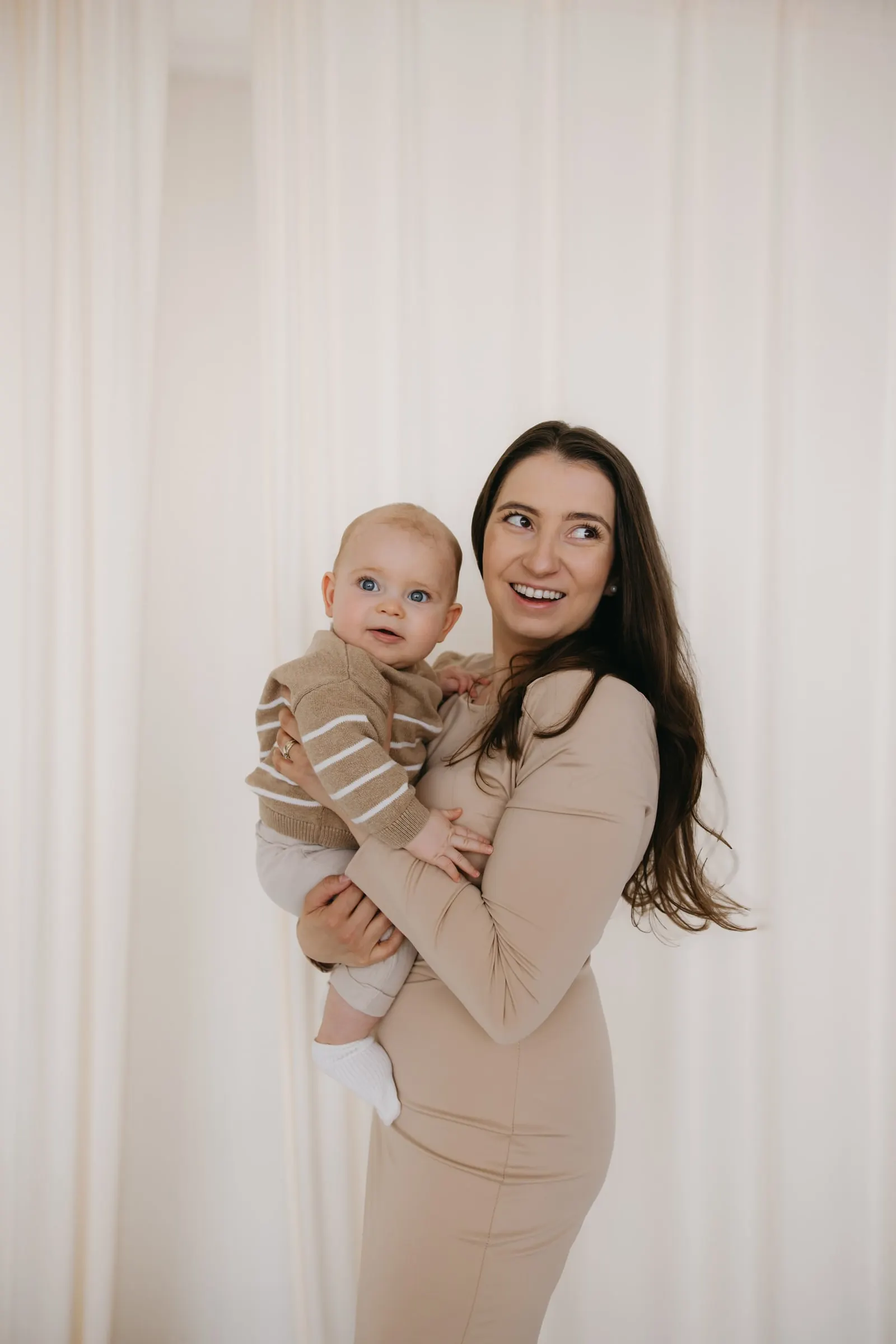 Mama s bábätkom pri bielom závese