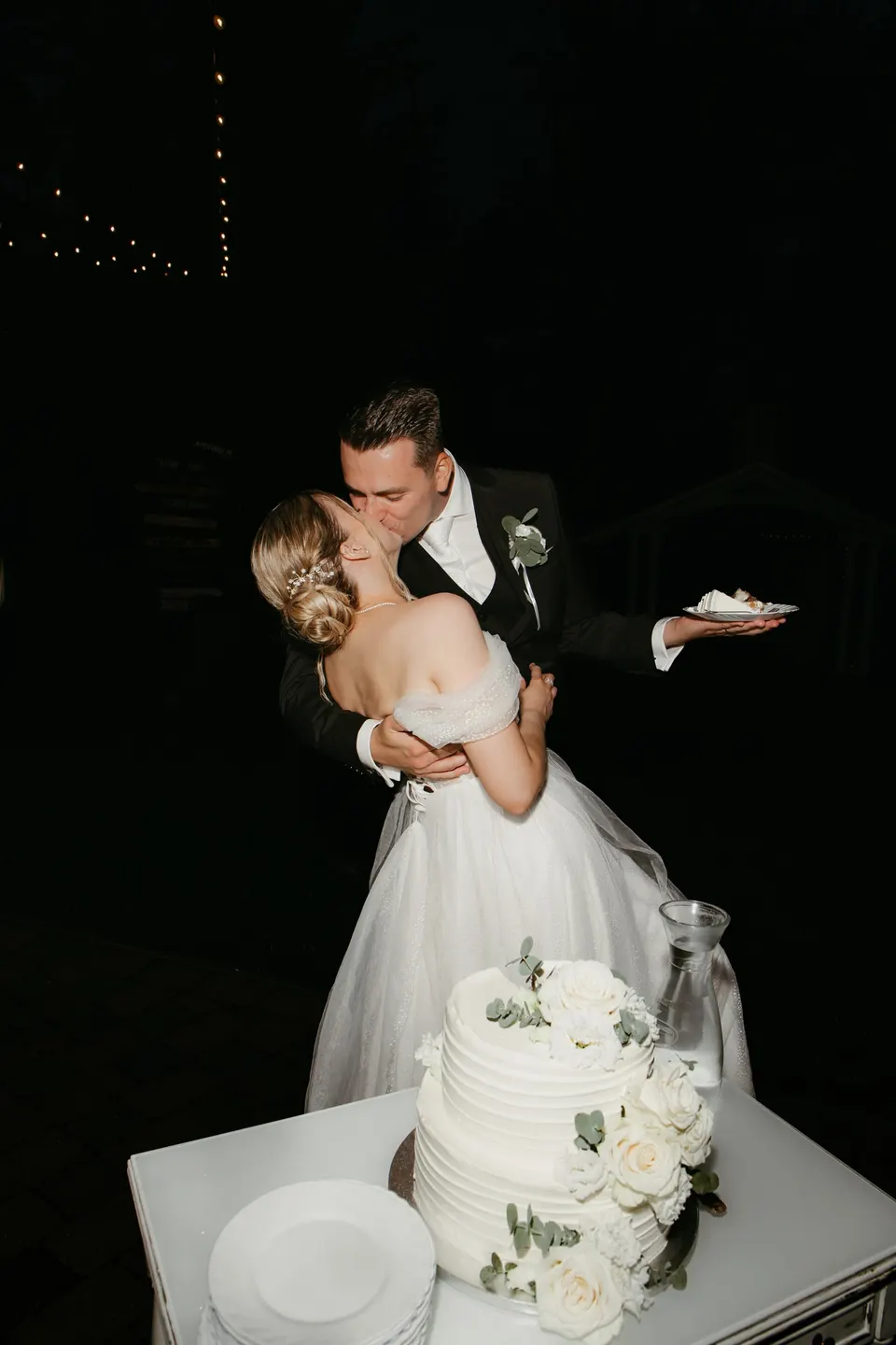 Novomanželia sa bozkávajú pri svadobnej torte
