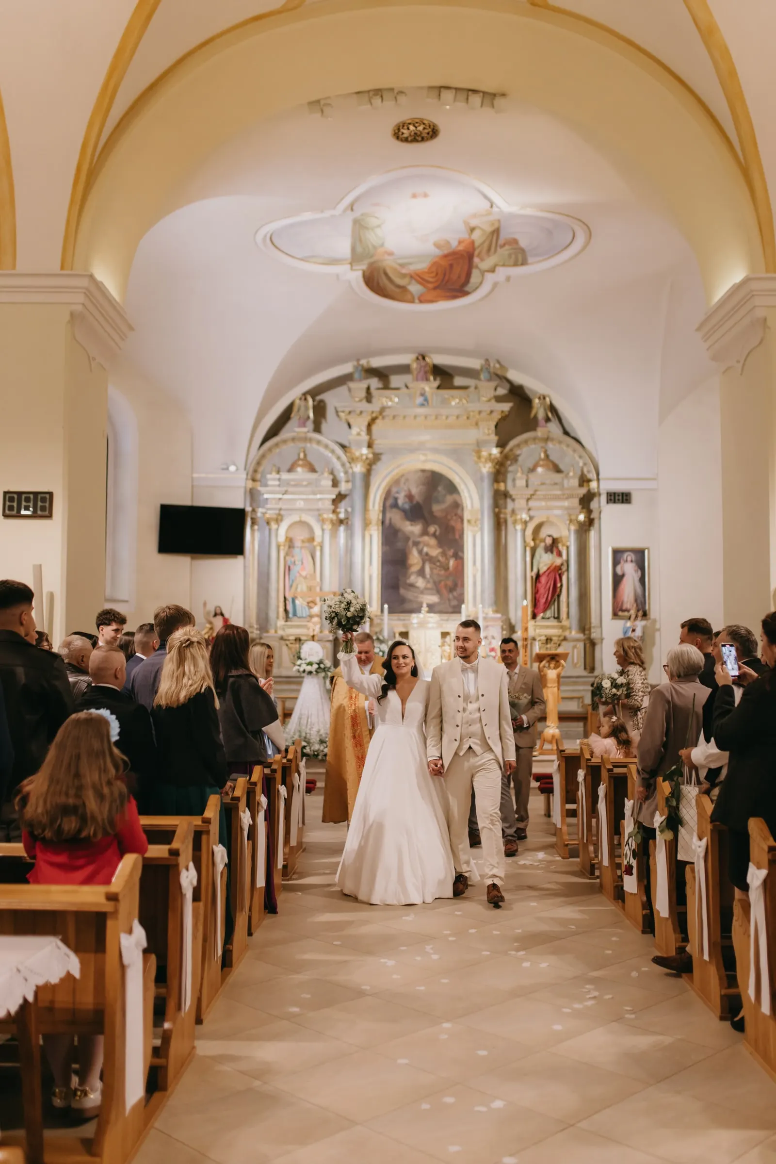 Novomanželia odchádzajú od oltára medzi hosťami