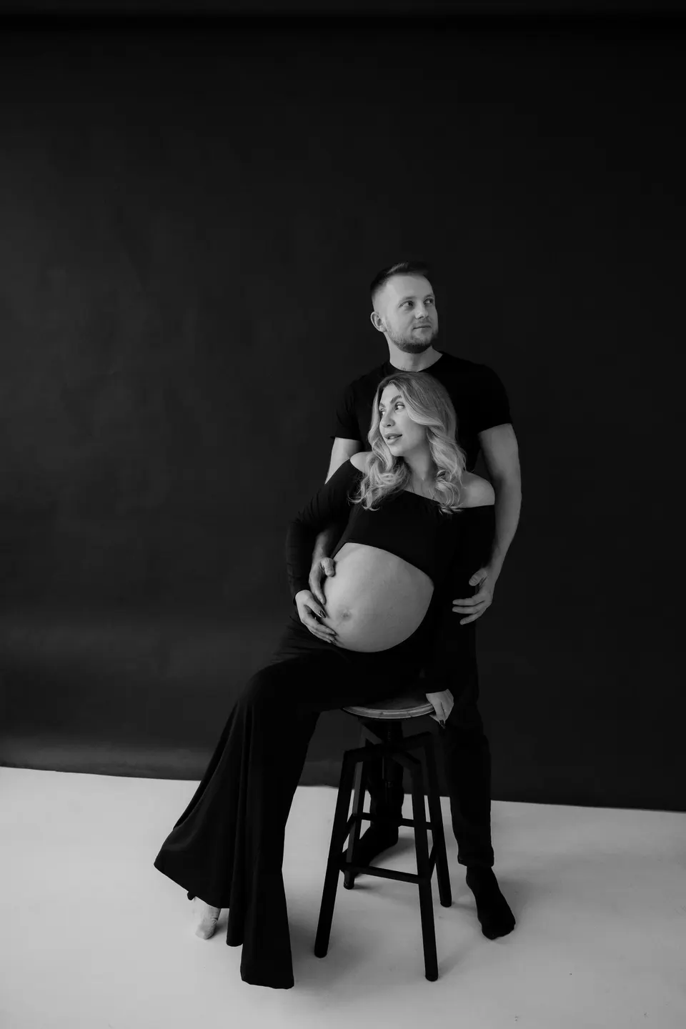 Budúci rodičia na tmavom pozadí, žena sedí na stoličke