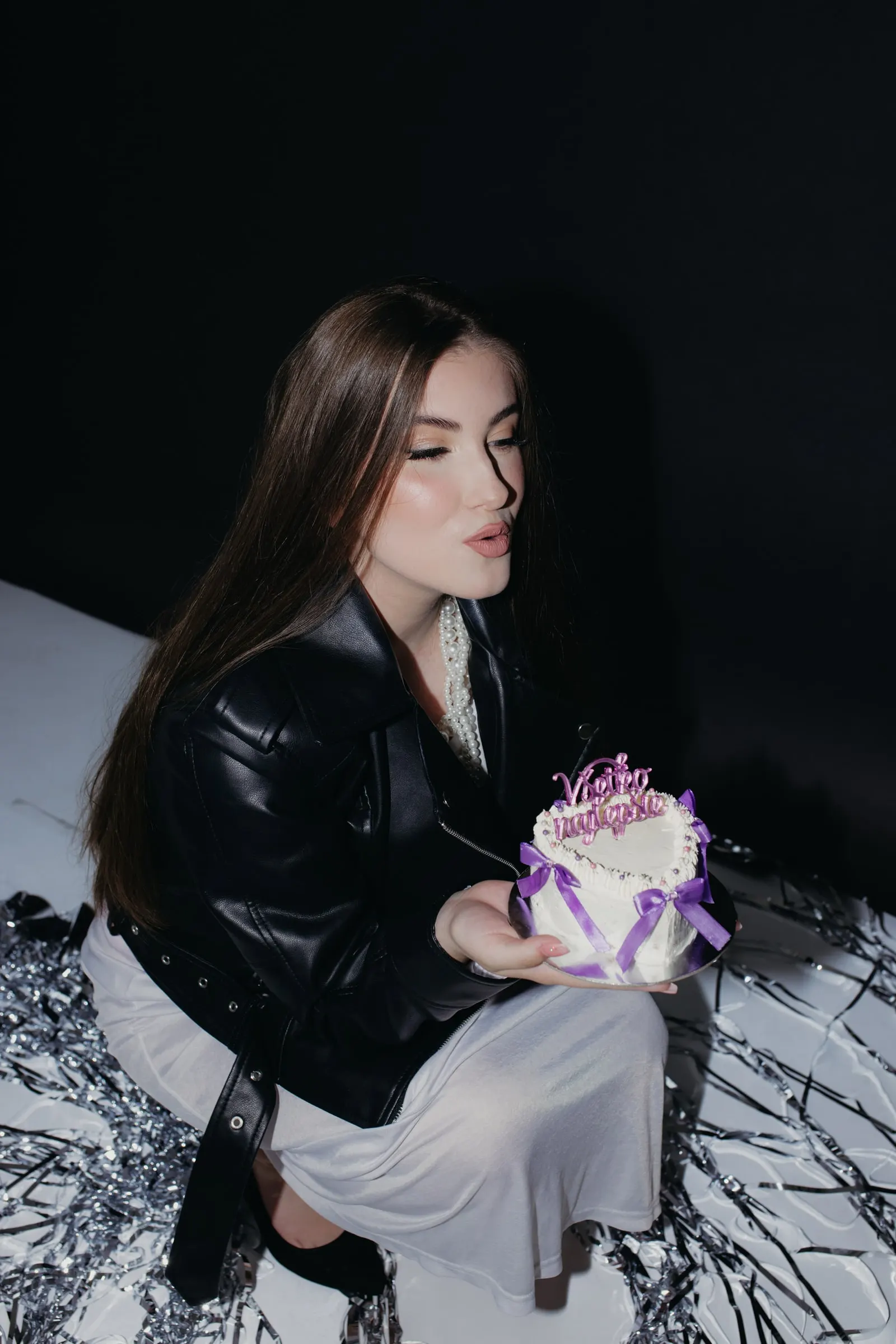Žena sfukuje sviečky na torte